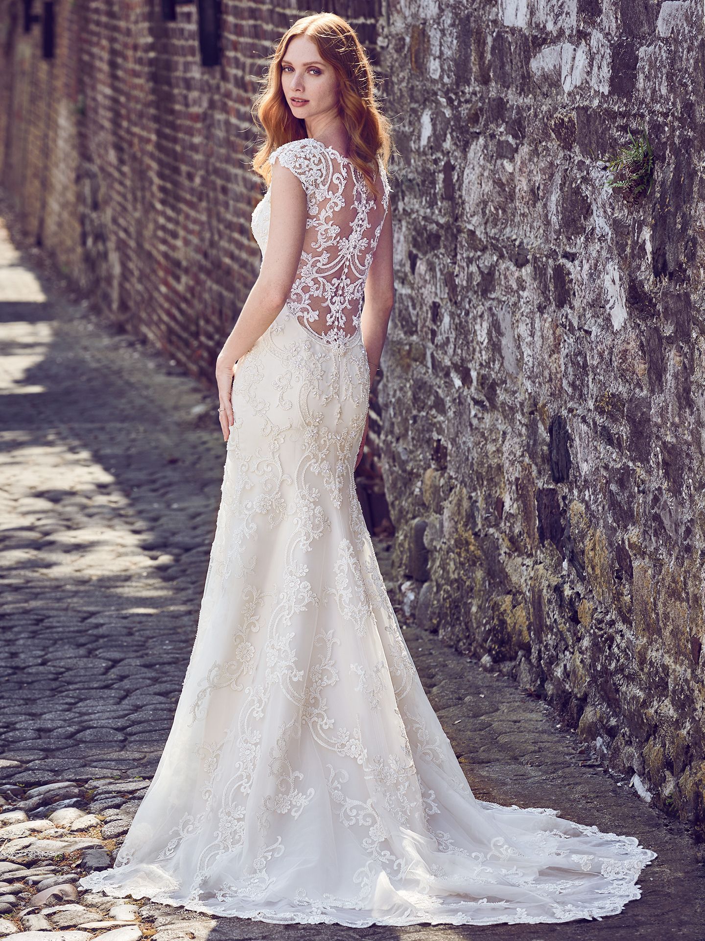 Everly by Maggie Sottero. This elegant fit-and-flare wedding dress features a tulle overlay of beaded lace motifs, creating an illusion bateau over sweetheart neckline, illusion cap-sleeves, illusion scoop back, and beautiful scallop hemline. Finished with pearl buttons and zipper closure. Upcoming 2018 wedding dress trends from Maggie Sottero!